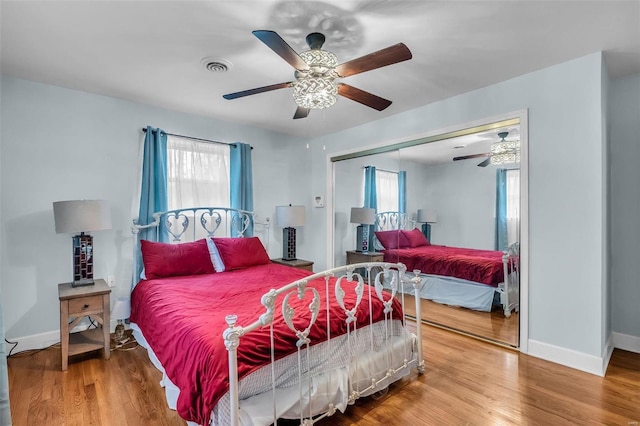 bedroom featuring ceiling fan, a closet, multiple windows, and hardwood / wood-style flooring