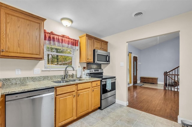 kitchen featuring sink, stainless steel appliances, and light stone counters