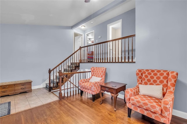 sitting room with ceiling fan, light wood-type flooring, and beamed ceiling