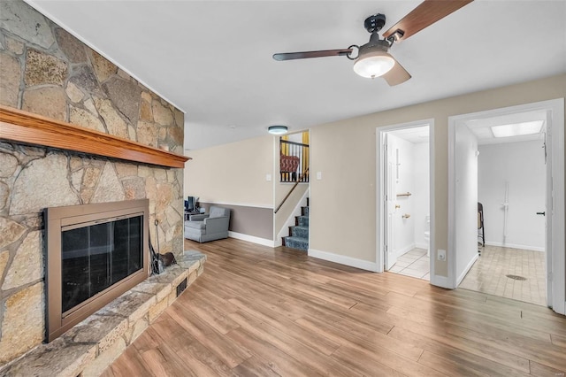 unfurnished living room featuring a fireplace, ceiling fan, and light hardwood / wood-style floors