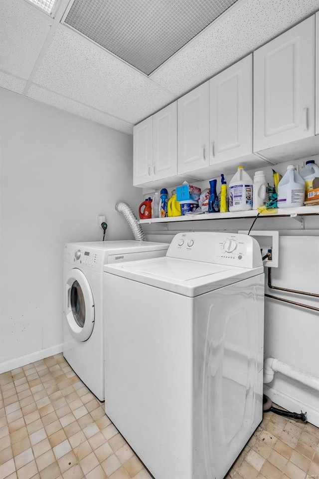 clothes washing area with cabinets and washing machine and dryer