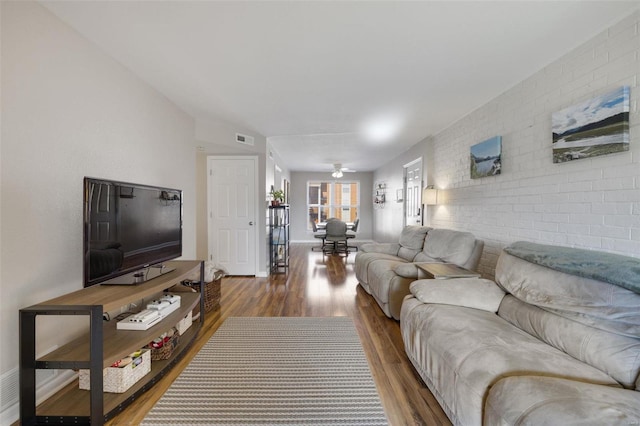 living room featuring ceiling fan, brick wall, lofted ceiling, and hardwood / wood-style flooring