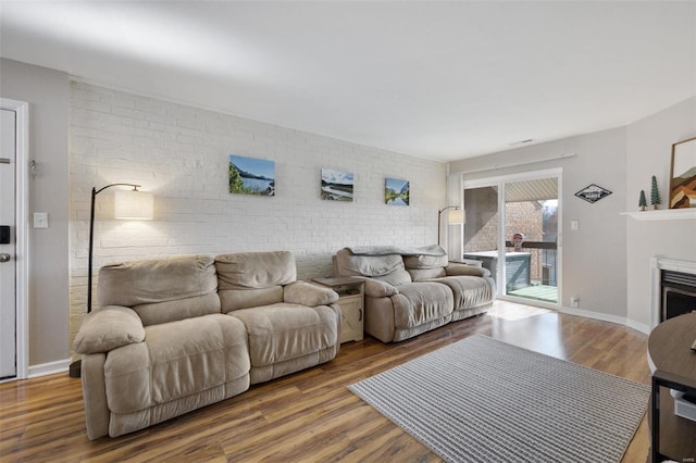 living room featuring hardwood / wood-style flooring and brick wall