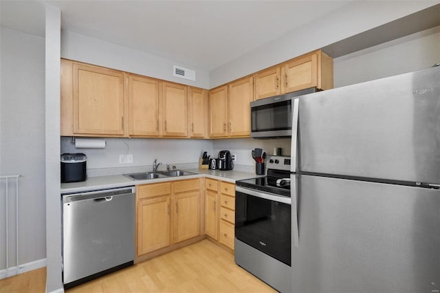 kitchen with light brown cabinets, sink, light hardwood / wood-style floors, and stainless steel appliances