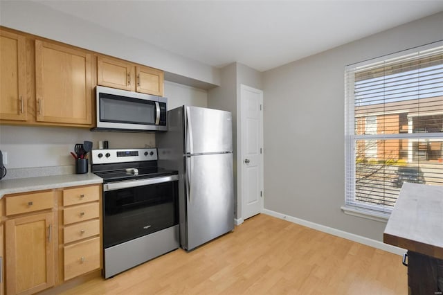 kitchen with light brown cabinetry, stainless steel appliances, light hardwood / wood-style flooring, and a healthy amount of sunlight