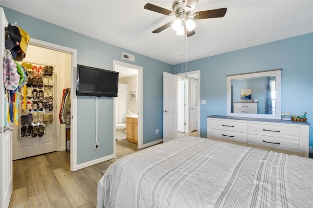 bedroom featuring light wood-type flooring, ceiling fan, and connected bathroom