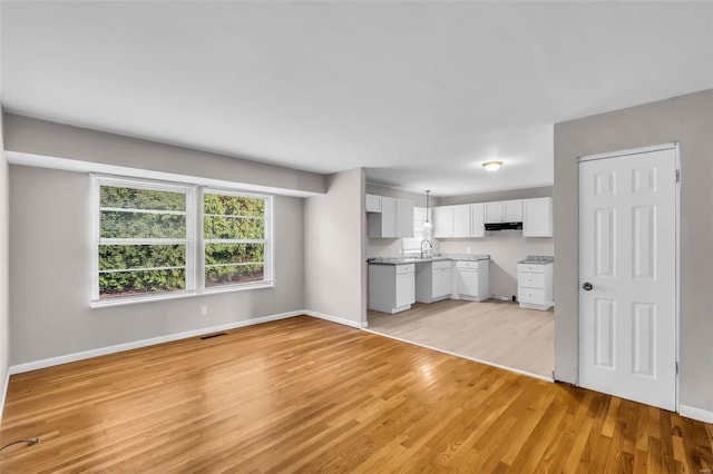 kitchen featuring dishwasher, light hardwood / wood-style flooring, white cabinets, and pendant lighting