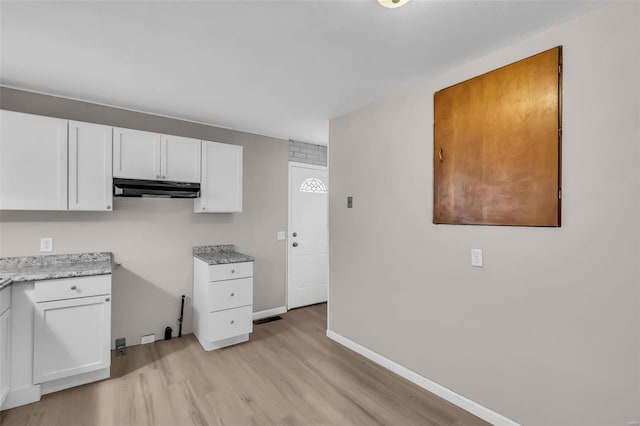 kitchen with light stone countertops, light hardwood / wood-style flooring, and white cabinetry