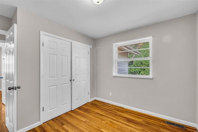 unfurnished bedroom with light wood-type flooring and a closet