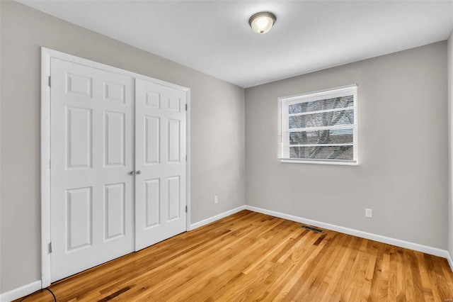 unfurnished bedroom with wood-type flooring and a closet