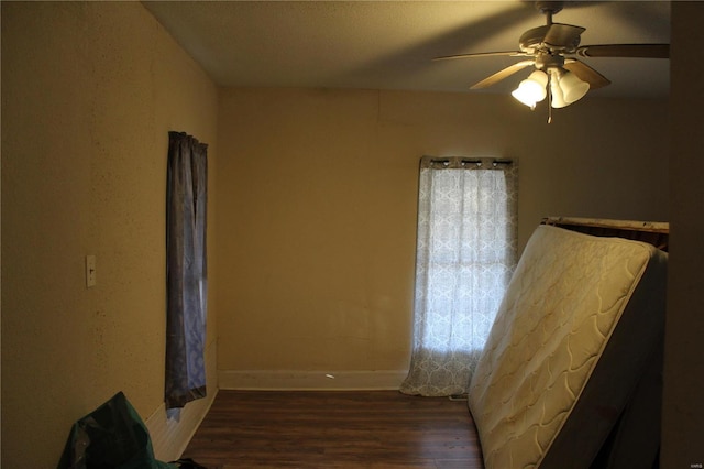 unfurnished bedroom with ceiling fan and dark wood-type flooring