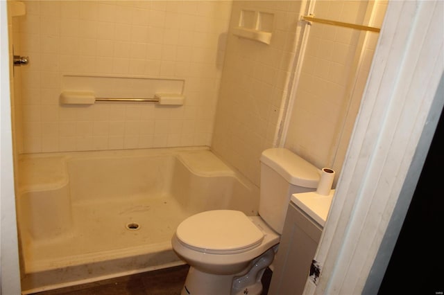 bathroom with tiled shower, vanity, and toilet