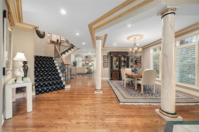 dining area featuring hardwood / wood-style floors, a chandelier, crown molding, and decorative columns