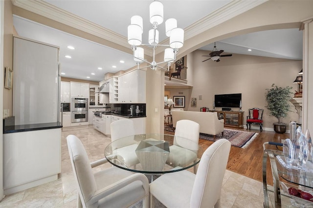 dining space with ceiling fan with notable chandelier, vaulted ceiling, light hardwood / wood-style flooring, and ornamental molding