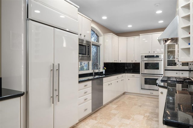 kitchen with white cabinetry, sink, tasteful backsplash, ventilation hood, and built in appliances