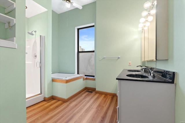 bathroom with wood-type flooring, vanity, and plus walk in shower