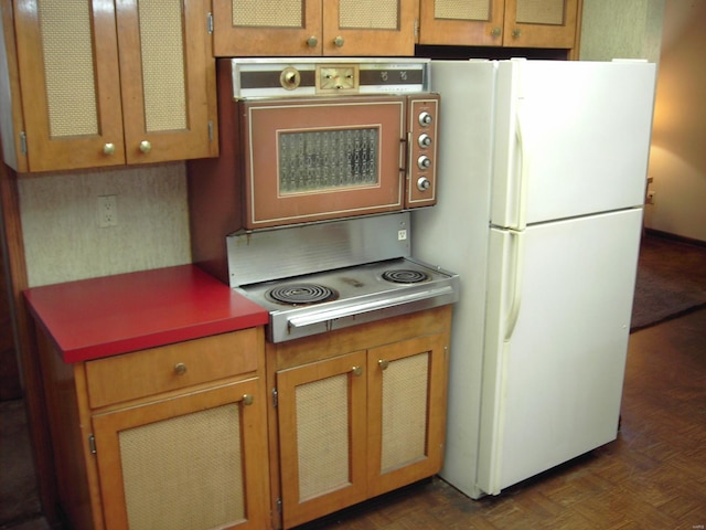 kitchen with oven, white fridge, cooktop, and dark parquet floors