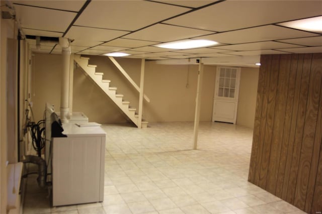 basement featuring a paneled ceiling and wood walls