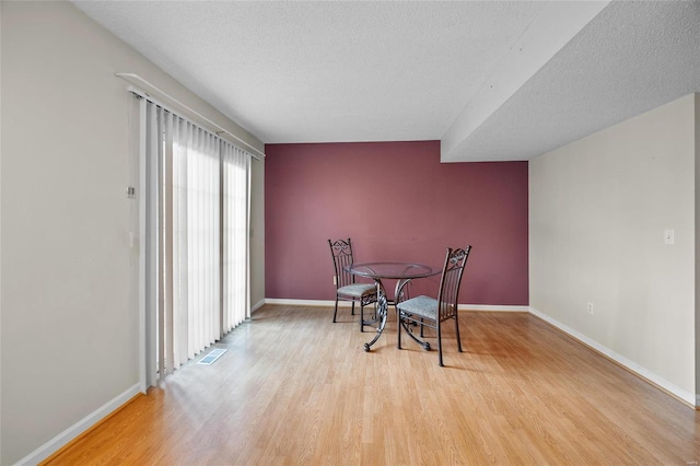 dining space featuring a textured ceiling and light wood-type flooring