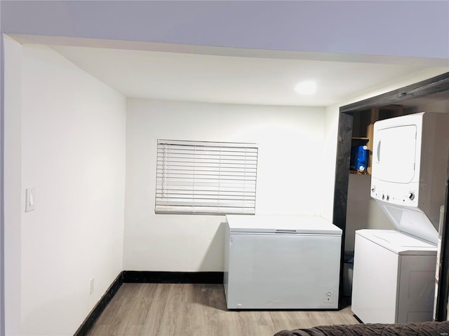 clothes washing area featuring stacked washer / drying machine and hardwood / wood-style flooring