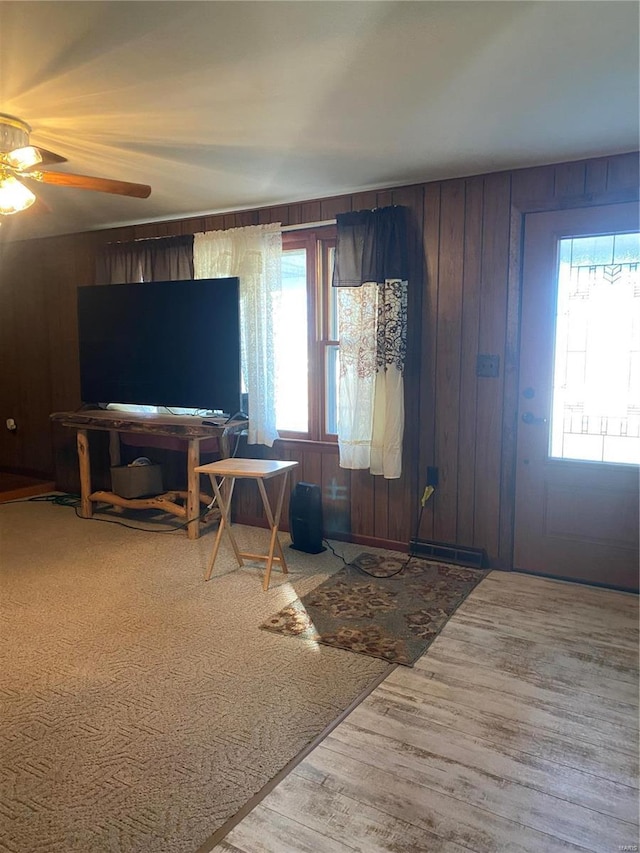 foyer entrance with hardwood / wood-style flooring, plenty of natural light, wooden walls, and ceiling fan