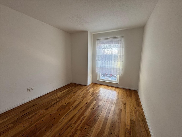 spare room featuring wood-type flooring and a textured ceiling