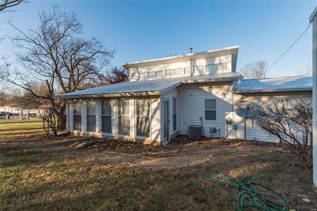 back of property featuring a sunroom, central AC unit, and a lawn