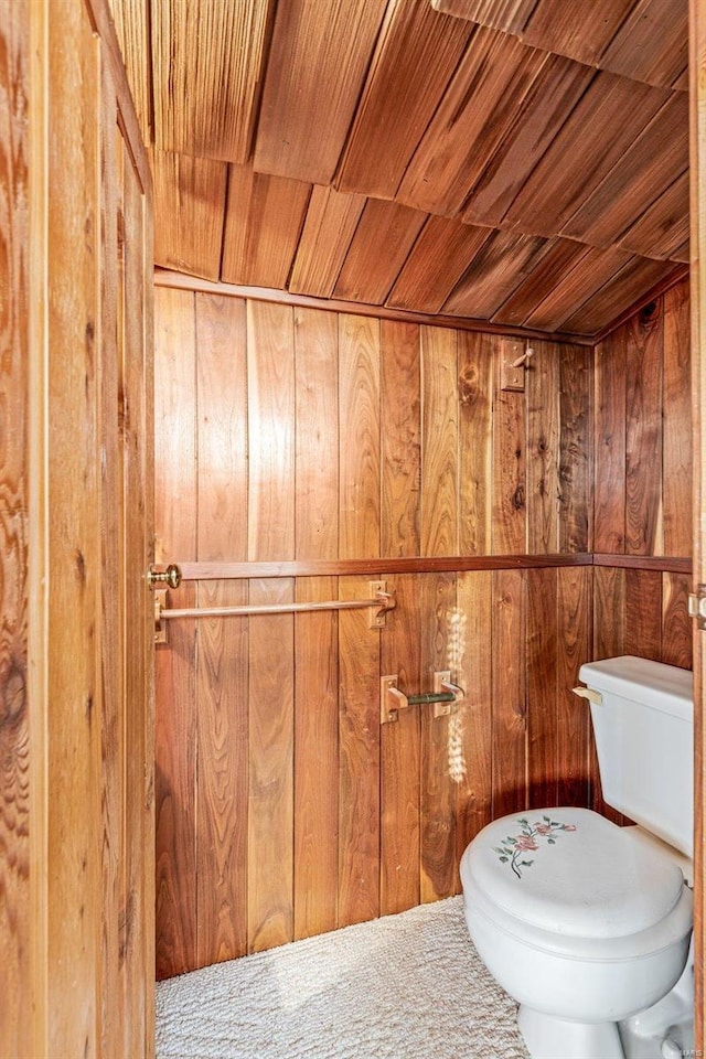 bathroom featuring wood walls, wood ceiling, and toilet