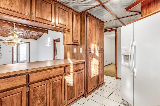 kitchen with ceiling fan, white refrigerator with ice dispenser, lofted ceiling, decorative light fixtures, and light tile patterned flooring