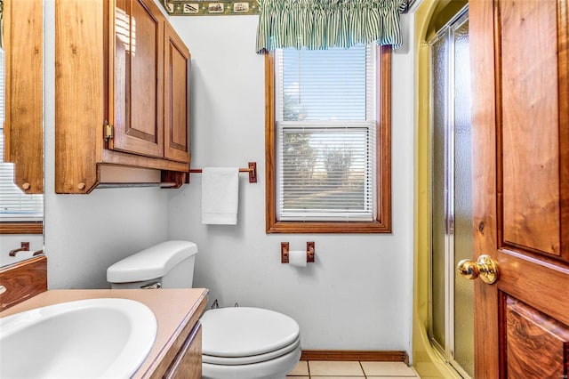 bathroom with tile patterned floors, a wealth of natural light, vanity, and toilet