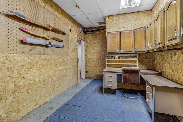 home office with a paneled ceiling and a workshop area