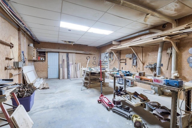 basement featuring a workshop area, a drop ceiling, and a wall mounted AC