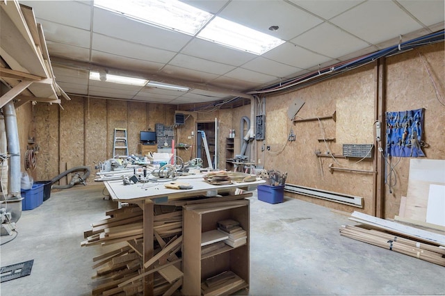 basement featuring a workshop area, a drop ceiling, and a baseboard radiator