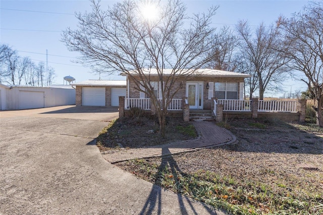 single story home featuring a porch, a garage, and an outdoor structure