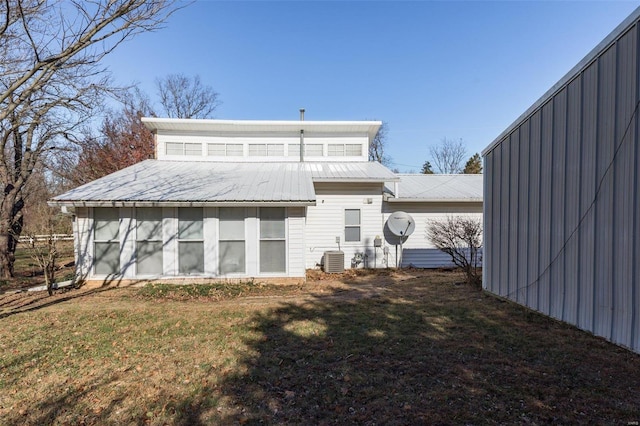 back of property with a lawn and central AC