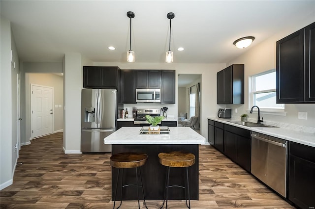 kitchen featuring appliances with stainless steel finishes, sink, wood-type flooring, pendant lighting, and a center island