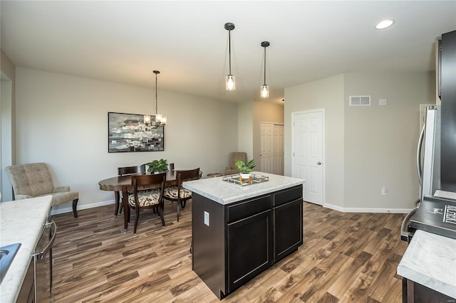 kitchen featuring hardwood / wood-style flooring, a center island, hanging light fixtures, and a chandelier