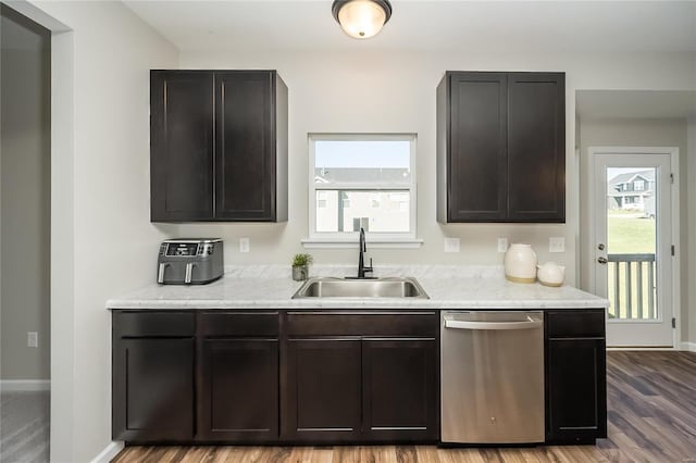 kitchen featuring sink, stainless steel dishwasher, dark brown cabinets, and hardwood / wood-style flooring