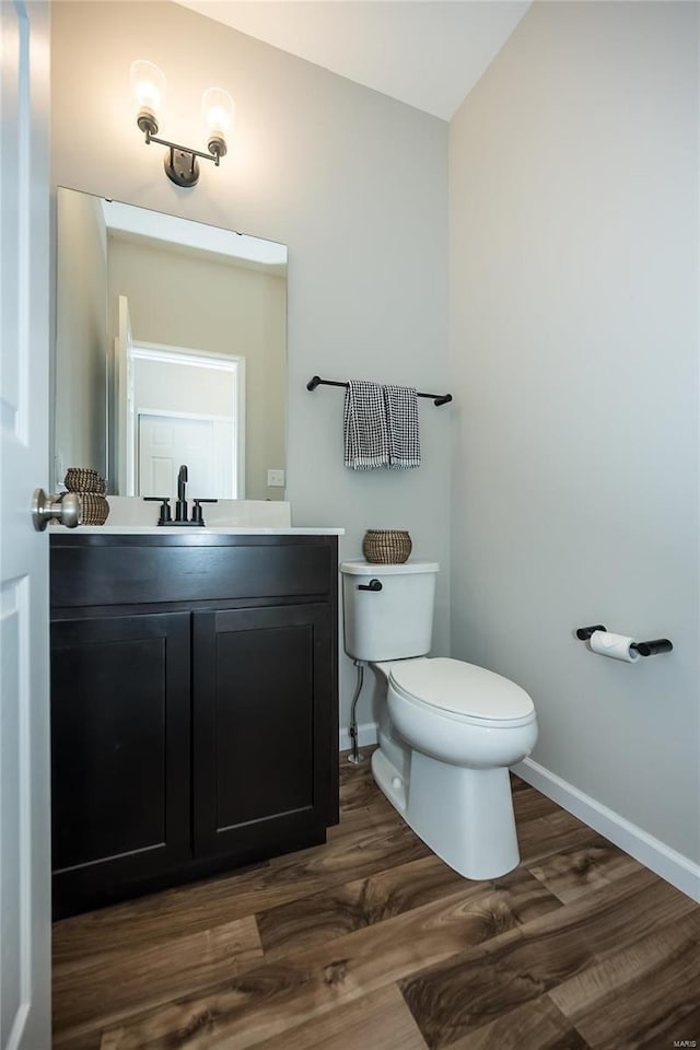 bathroom with hardwood / wood-style floors, vanity, and toilet