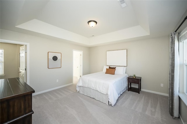 bedroom with a raised ceiling and light carpet