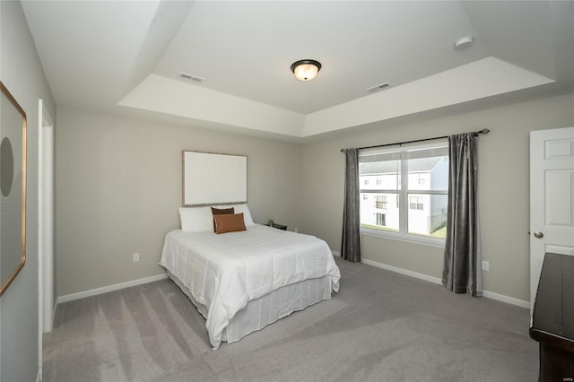 bedroom featuring light colored carpet and a tray ceiling