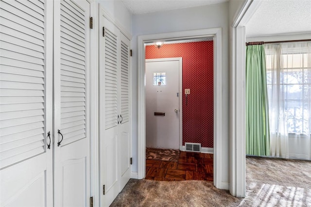 hallway featuring dark carpet and a textured ceiling