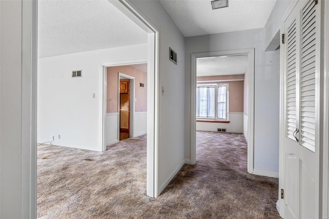 corridor featuring dark carpet and a textured ceiling