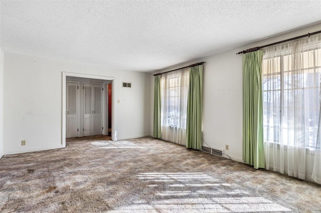 carpeted spare room with a textured ceiling