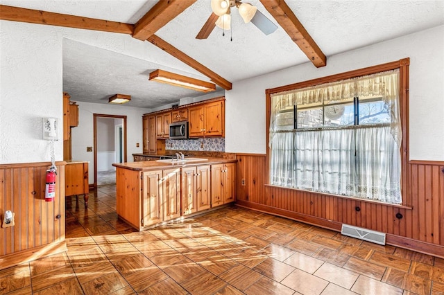 kitchen featuring kitchen peninsula, beam ceiling, a textured ceiling, and sink