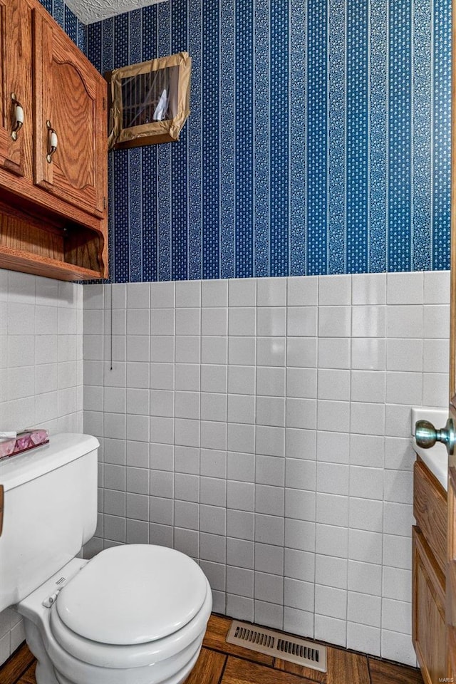 bathroom with tile walls and toilet