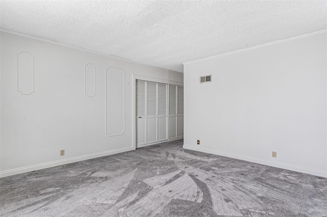 empty room featuring light carpet, a textured ceiling, and ornamental molding