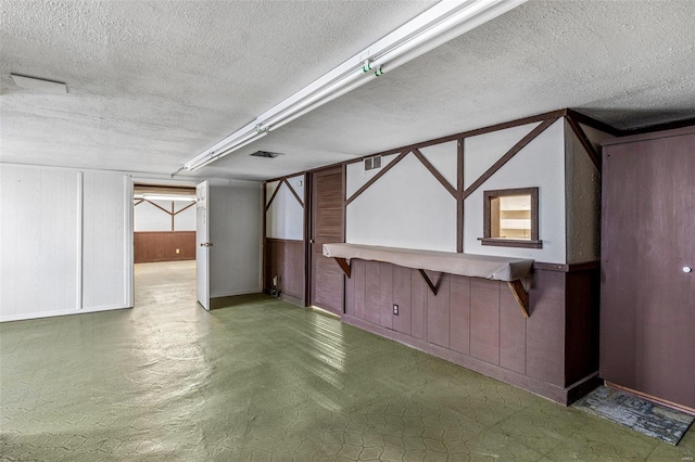 basement featuring wooden walls and a textured ceiling