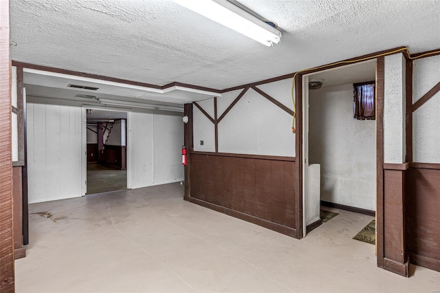 basement featuring wooden walls and a textured ceiling