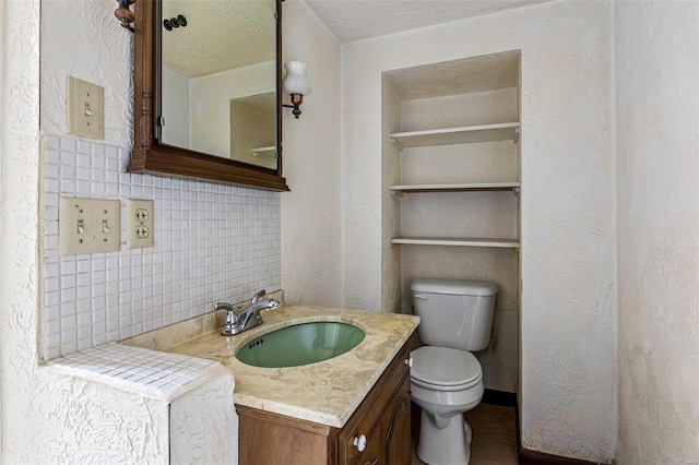 bathroom featuring decorative backsplash, toilet, a textured ceiling, and vanity